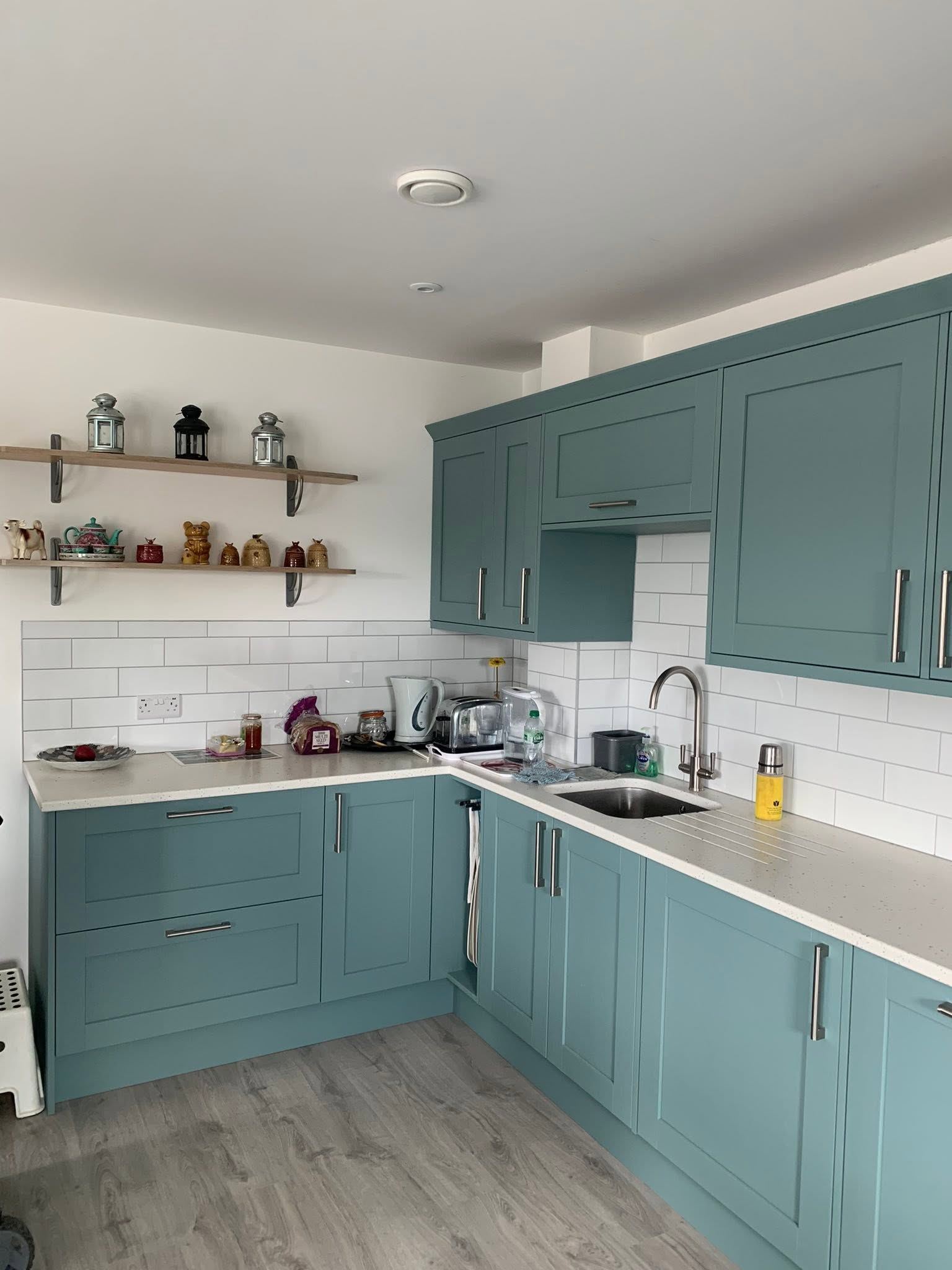 Finished kitchen with sage green units and white metro tiles